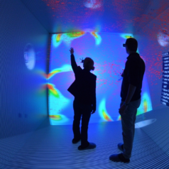 Two persons with VR-glasses in a blue-lighted room.